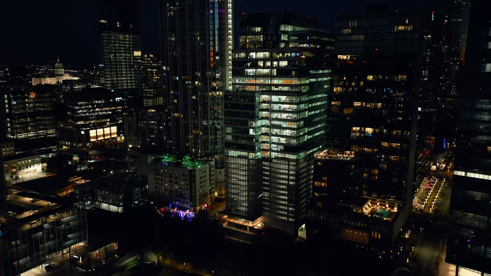 A city at night from the air: lit towers and busy streets.
